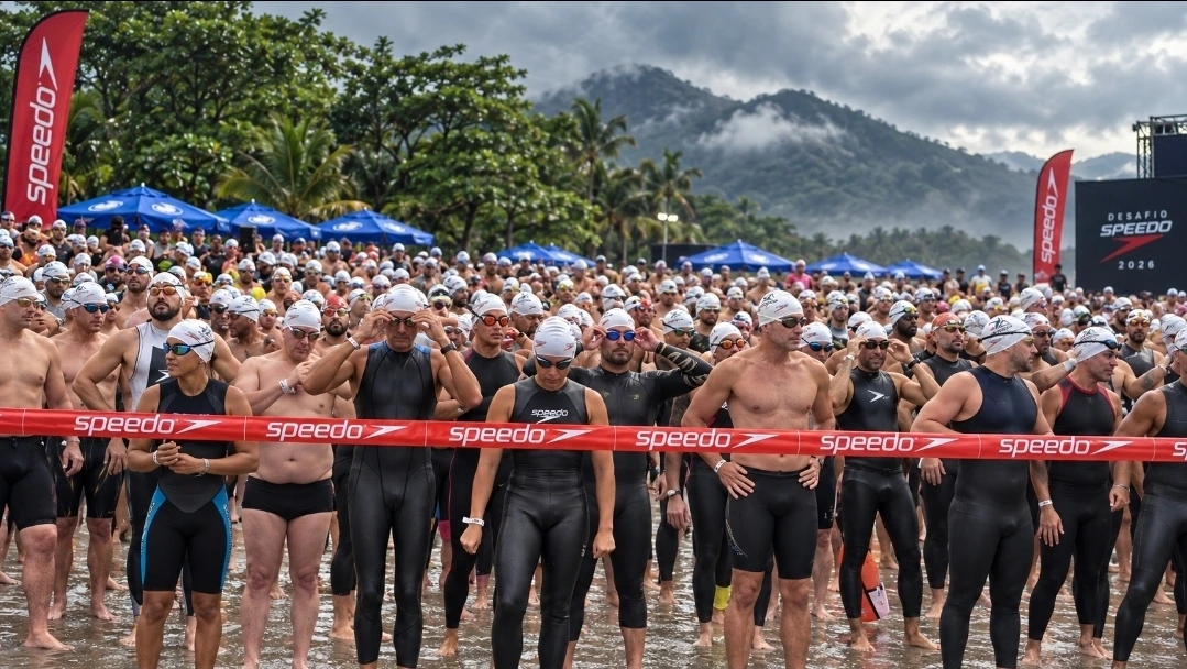 Imagem de campanha: nadadores se preparando para a largada atrás da faixa Speedo, com montanhas e neblina ao fundo
